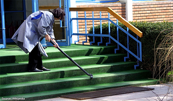 A lady is cleaning in front of her house