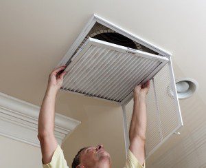 Man removing filter from ceiling air duct cleaning