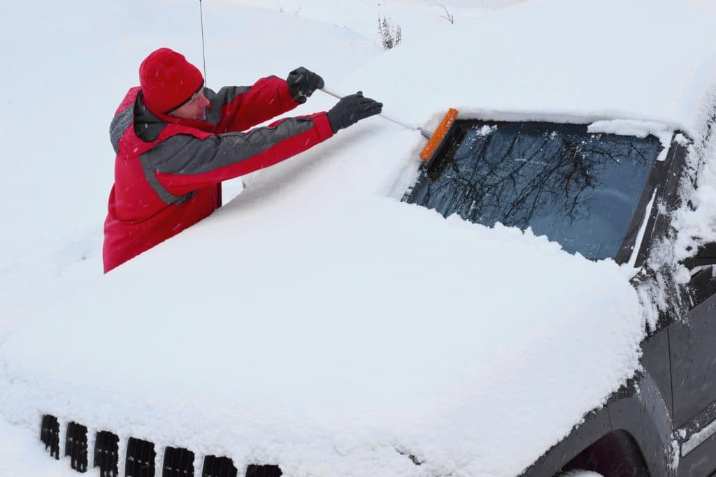 Man removing snow off of car