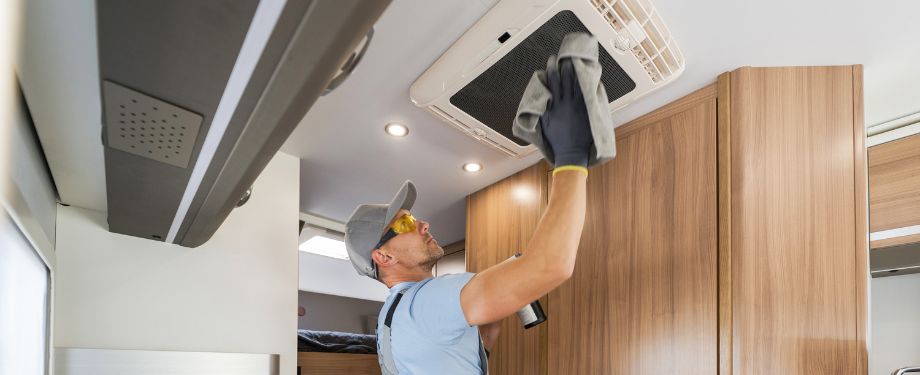RV Rental Company Worker Cleaning Motorhome Air Condition Unit RV Rental Company Worker Cleaning Motorhome Air Condition Unit
